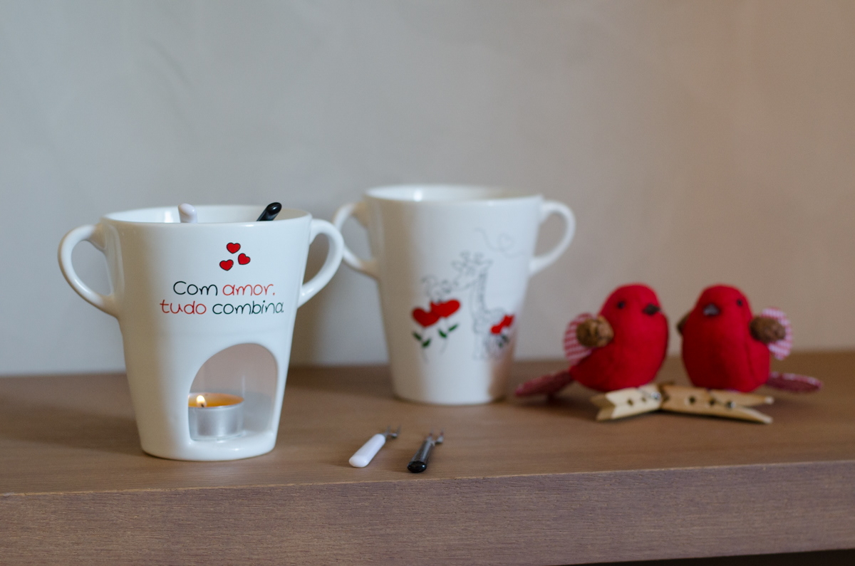 A porcelain fondue cup with an illustration of a giraffe and a squirrel in love. On the back of the cup, it says "With love, everything matches."