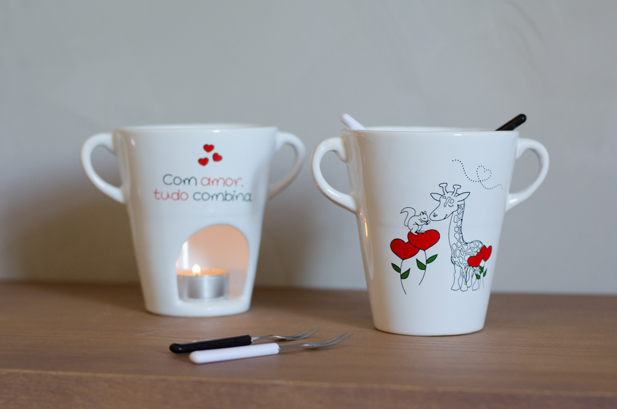 A porcelain fondue cup with an illustration of a giraffe and a squirrel in love. On the back of the cup, it says "With love, everything matches."