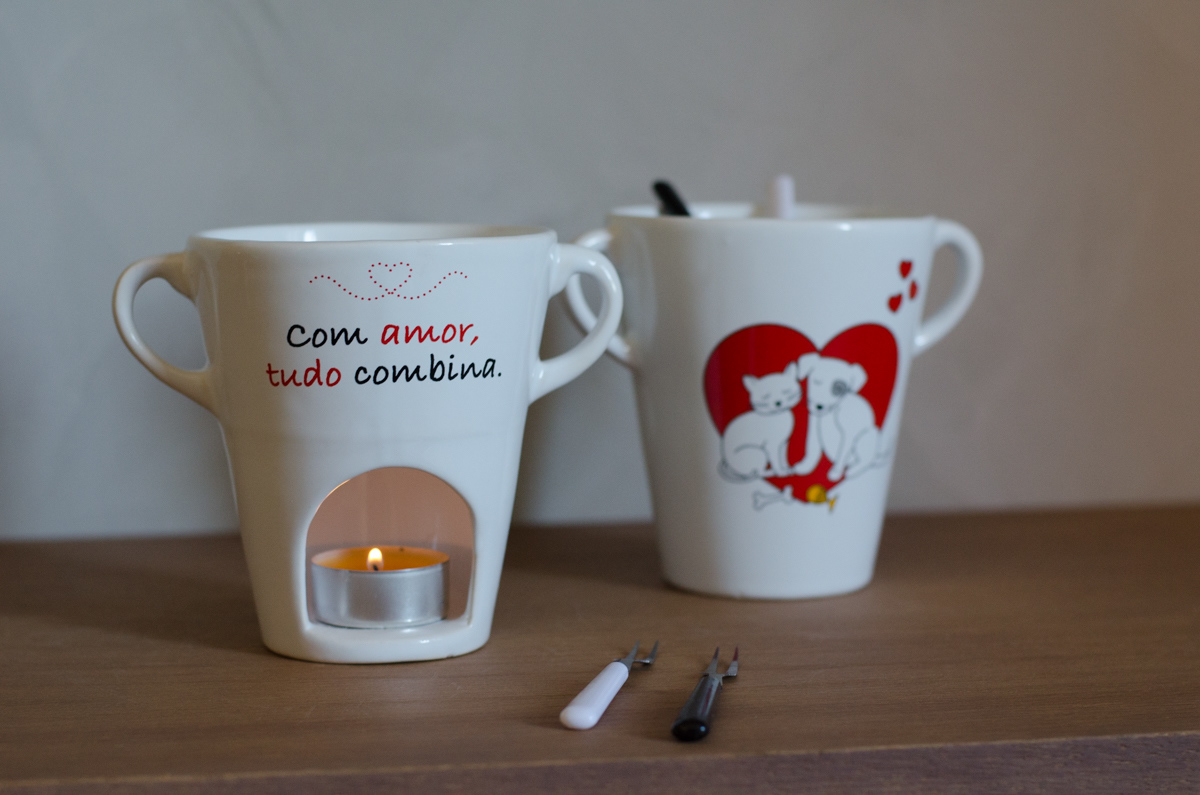 A porcelain fondue cup with an illustration of a cat and a dog in love. On the back of the cup, it says "With love, everything matches."
