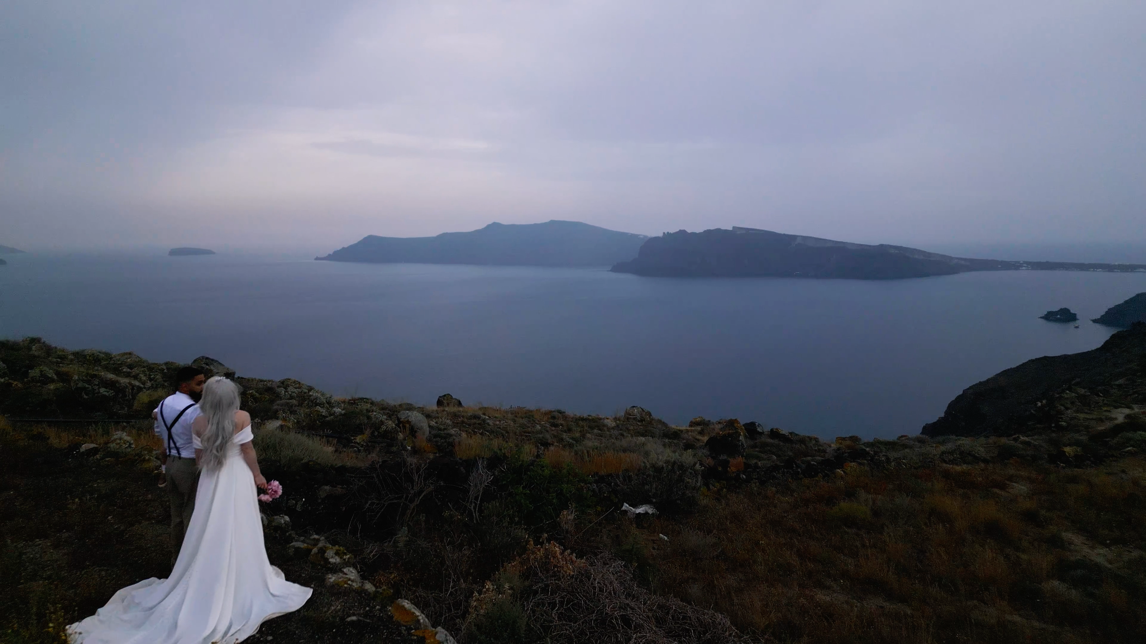 Cinematic shot of a couple, cliffside, in Santorini Greece