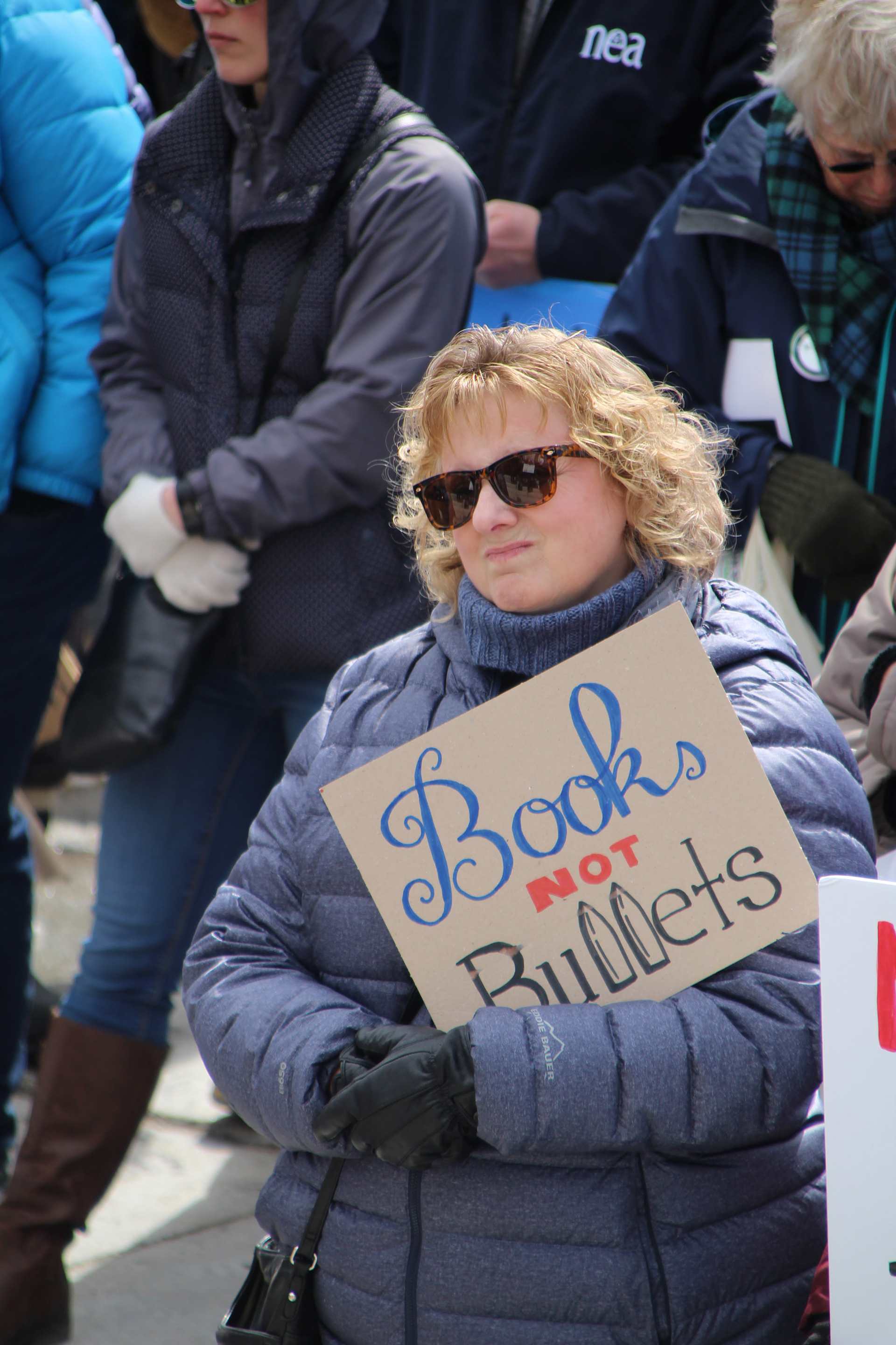 A woman looks into the crowd and holds a sign in protest in Montpelier, Vt. on March 24, 2018. (Lia Chien)