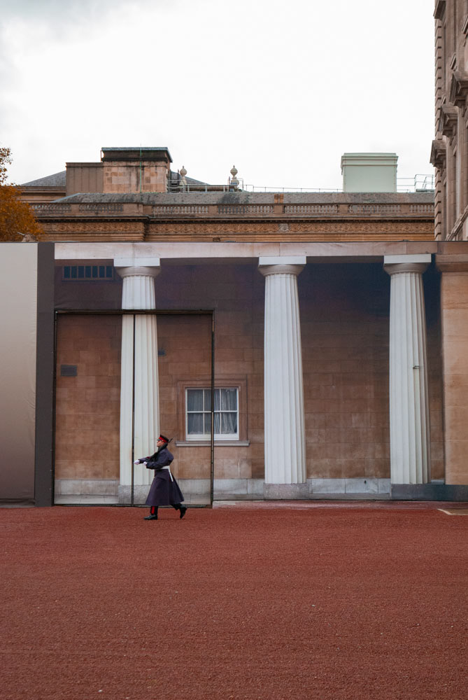 The second one is related to the fake scene in the background. Even if it seems very realistic, on a second glance we can see that the guard is marching in front of a gigantic picture of the building.