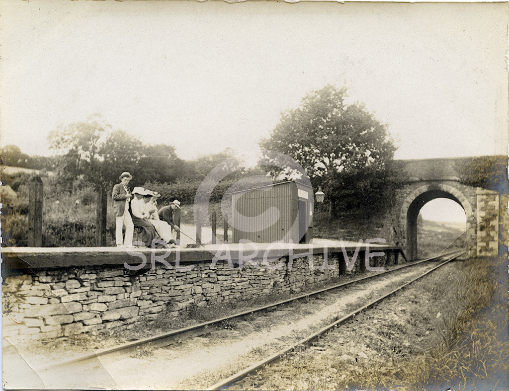 St Keyne Wishing Well Halt opened in October 1902 on the Liskeard-Looe line. Seen here prior to the line being taken over by the GWR in 1909. After the takeover most of the bridges required rebuilding to improve clearance for the large and heavier locomotives and rolling stock. Some Edwardian passengers wait on the platform for the next train. SRL No 391 