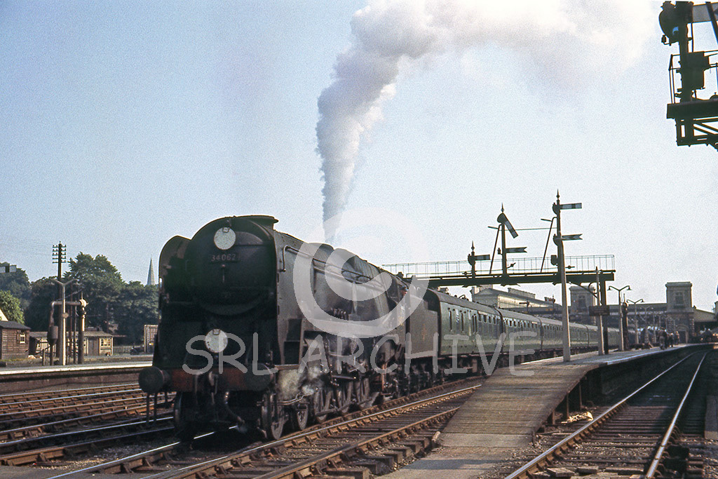 34062 '17 Squadron' blows off at Exeter St Davids station with an express for Waterloo around 1961 lovely signal gantry in the background SRL No 847 