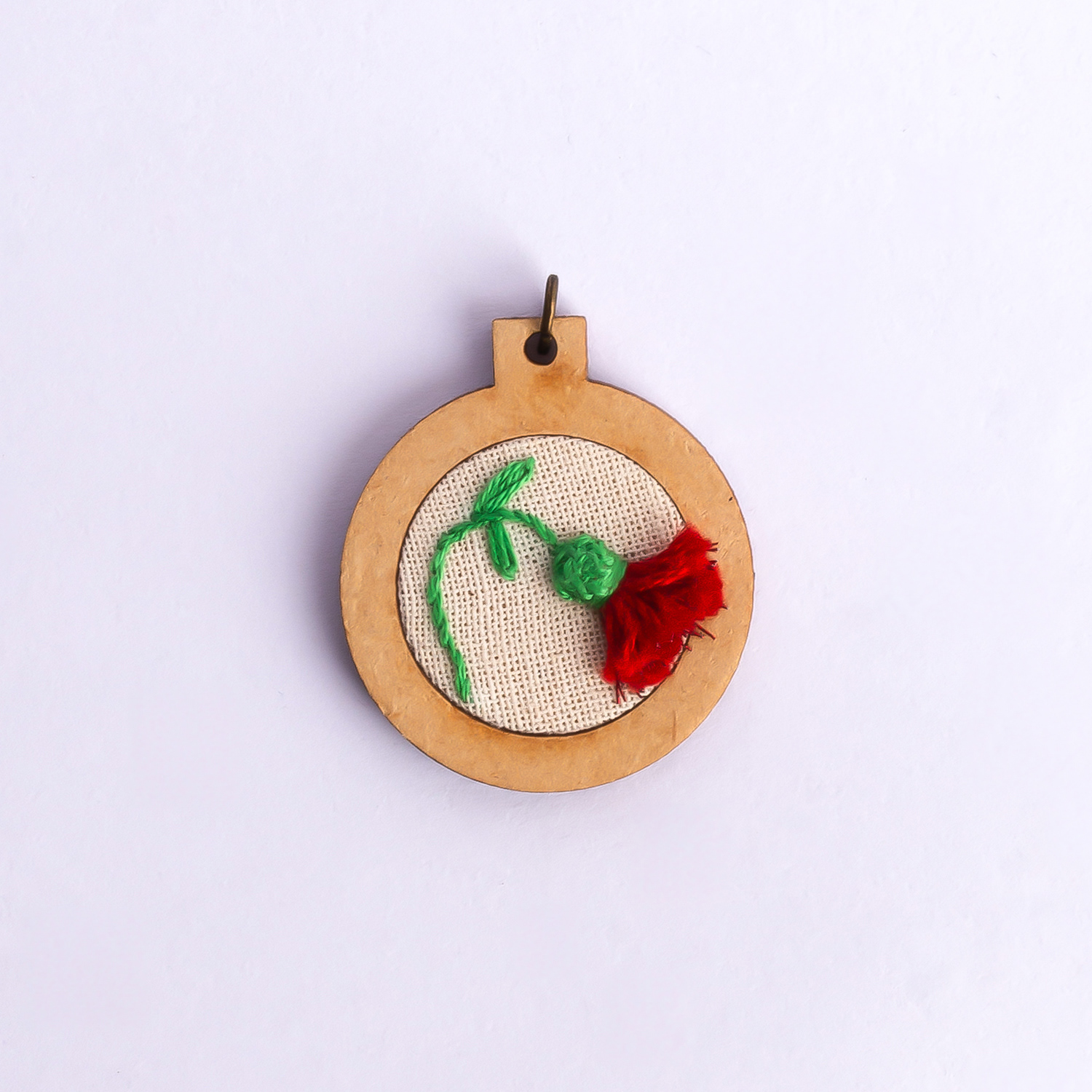 Dije bordado a mano con marco de madera y cordón de hilo encerado. Pieza única. Tamaño 3cm de diámetro. $10.000