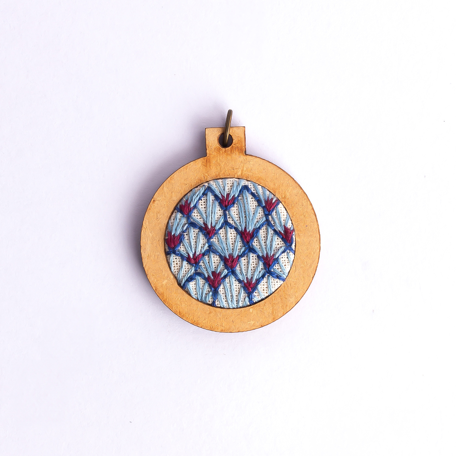 Dije bordado a mano con marco de madera y cordón de hilo encerado. Pieza única. Tamaño 3cm de diámetro. $10.000