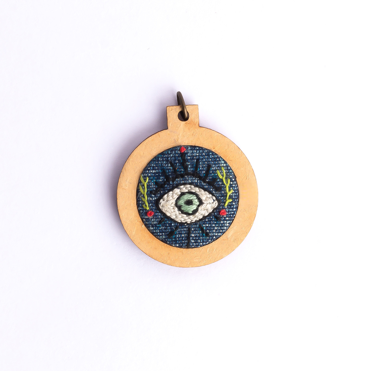 Dije bordado a mano con marco de madera y cordón de hilo encerado. Pieza única. Tamaño 3cm de diámetro. $10.000