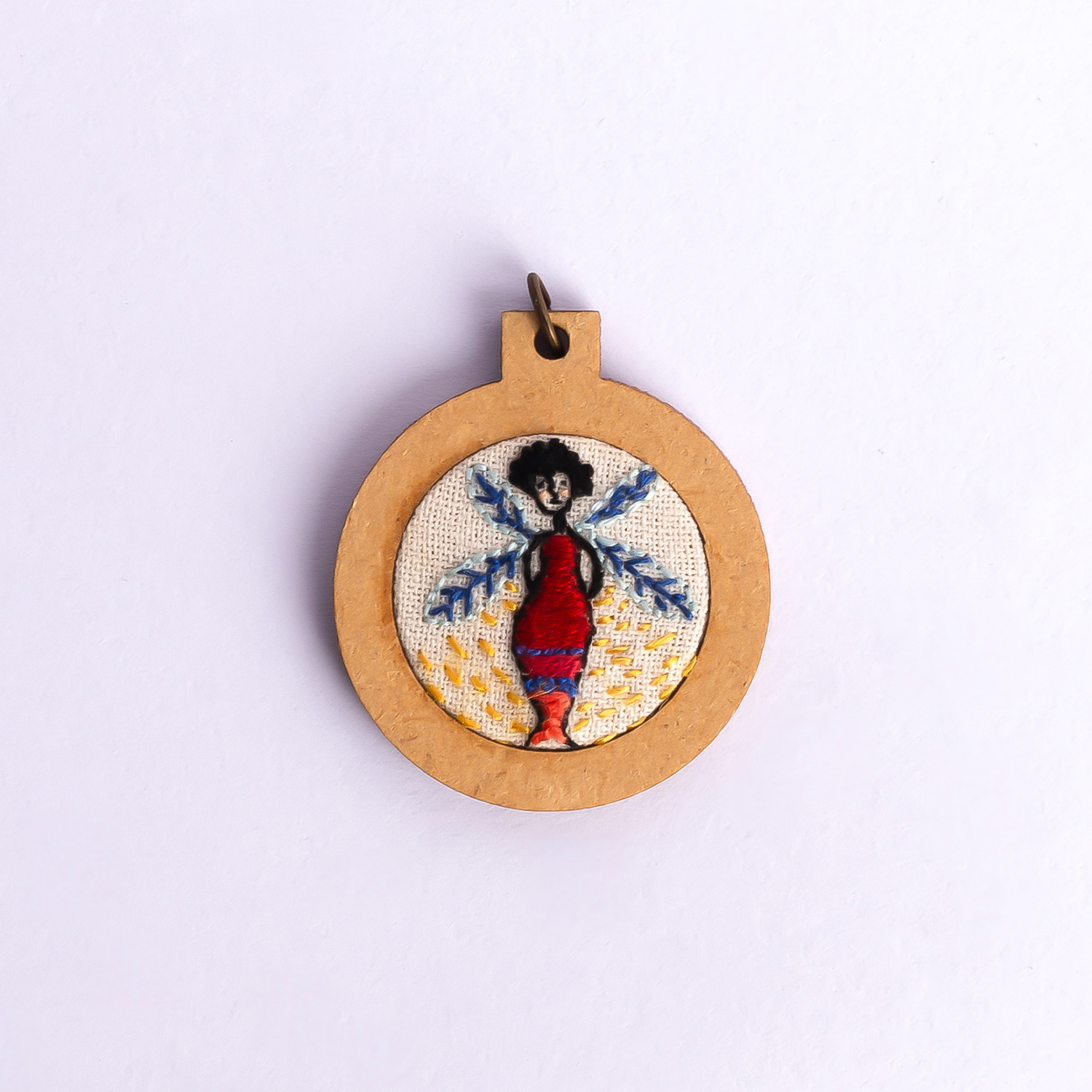 Dije bordado a mano con marco de madera y cordón de hilo encerado. Pieza única. Tamaño 3cm de diámetro. $10.000