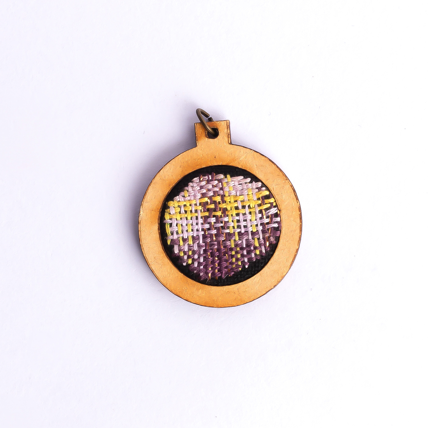 Dije bordado a mano con marco de madera y cordón de hilo encerado. Pieza única. Tamaño 3cm de diámetro. $10.000