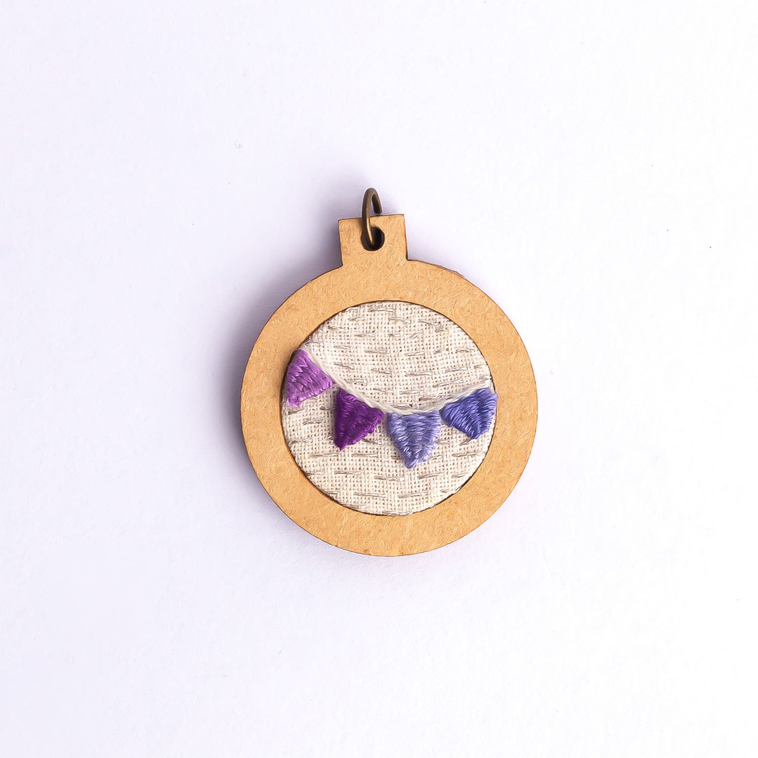 Dije bordado a mano con marco de madera y cordón de hilo encerado. Pieza única. Tamaño 3cm de diámetro. $10.000