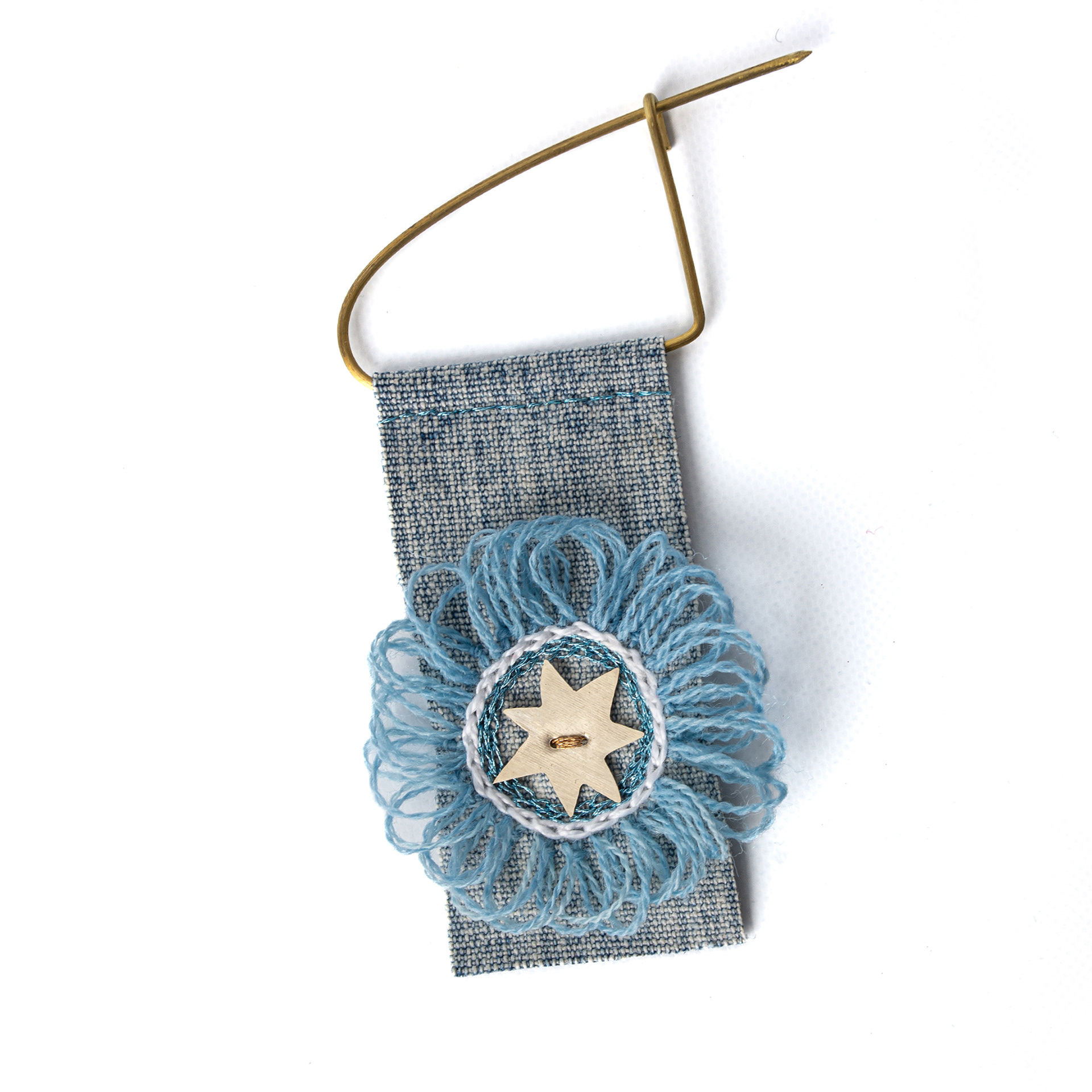 Escarapela bordada a mano, estrella de alpaca, soporte jean, gancho de bronce. $10.000