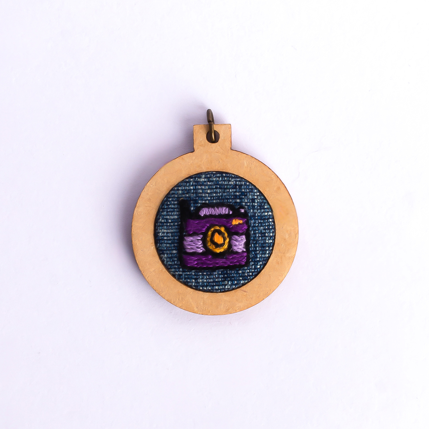 Dije bordado a mano con marco de madera y cordón de hilo encerado. Pieza única. Tamaño 3cm de diámetro. $10.000