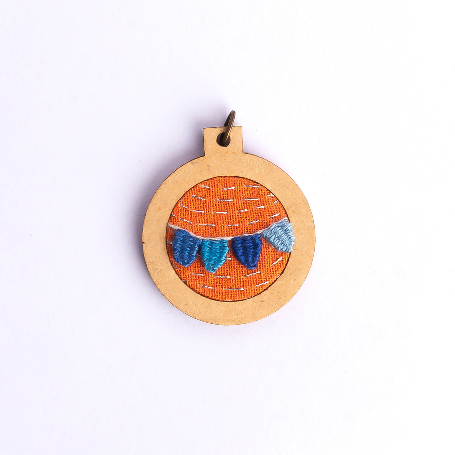 Dije bordado a mano con marco de madera y cordón de hilo encerado. Pieza única. Tamaño 3cm de diámetro. $10.000