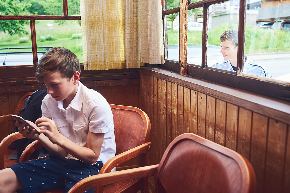 Invité assis dans une salle en bois, consultant son téléphone pendant un mariage.