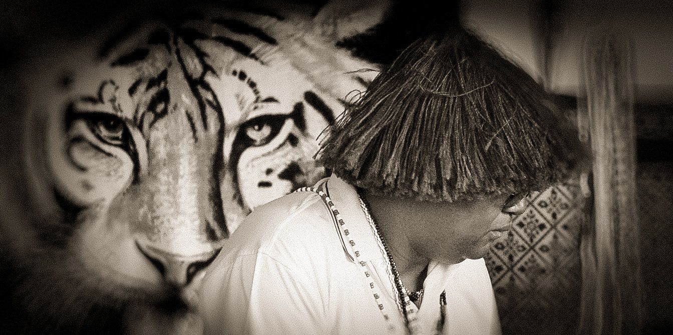 A straw hat covers his eyes. The male and senior sangoma is wearing the regular white, red and black cloth around his hips and a white t-shirt.  On top of the t-shirt, the beads in hundreds, or perhaps thousands. The beads and colours that make the living bow and clap. I accept and breathe in their presence. And acceptance has no reason to question.