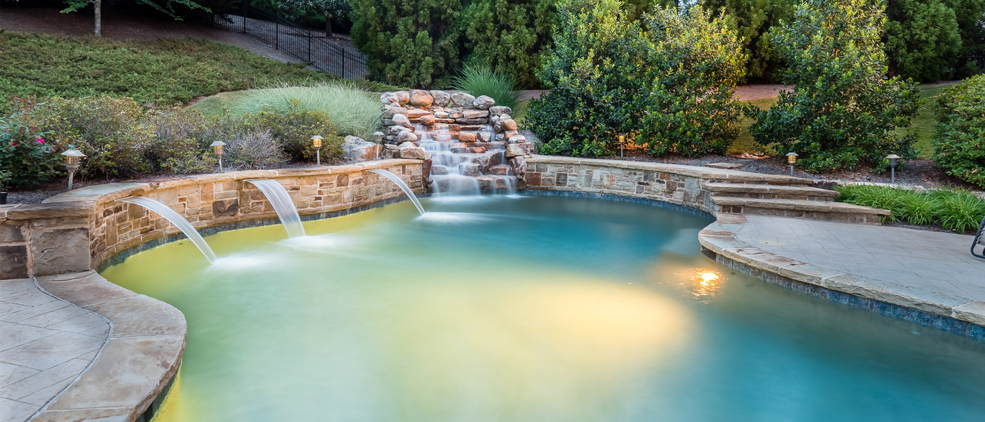 Long exposure photography captures silky flowing water in the shears and waterfall of a luxury home for sale in Milton, GA.  Residential real estate photograph by Cindy Kringelis of Alpharetta Photography for The Willnow Group. 