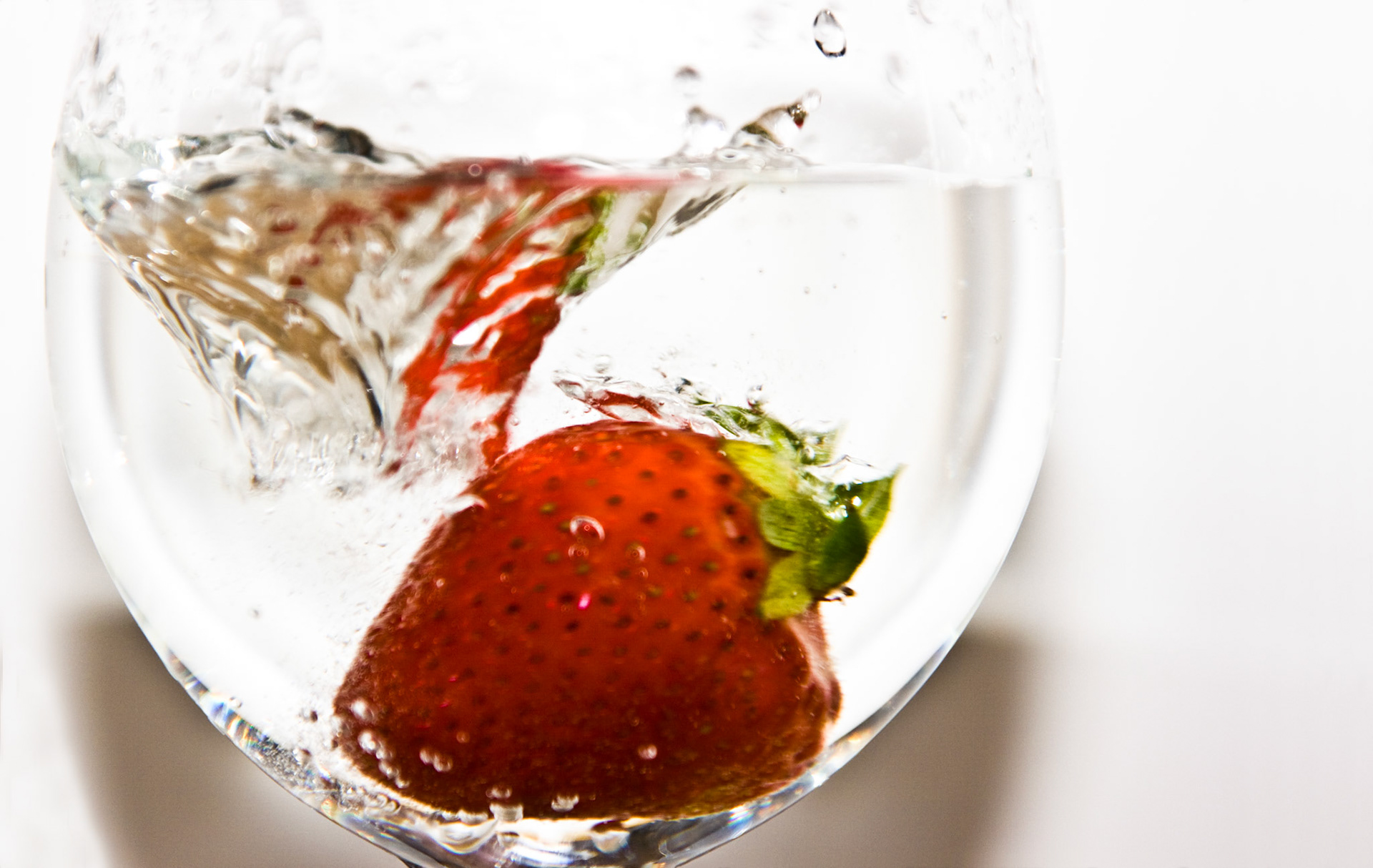 Todesmutig springt diese Erdbeere in eine volles Wasserglas.