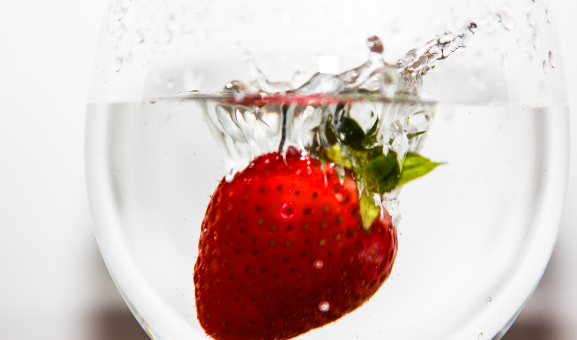 Todesmutig springt diese Erdbeere in eine volles Wasserglas.