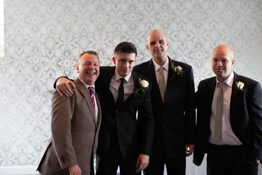 Groom and groomsmen huddle together for a natural, relaxed group photo.
