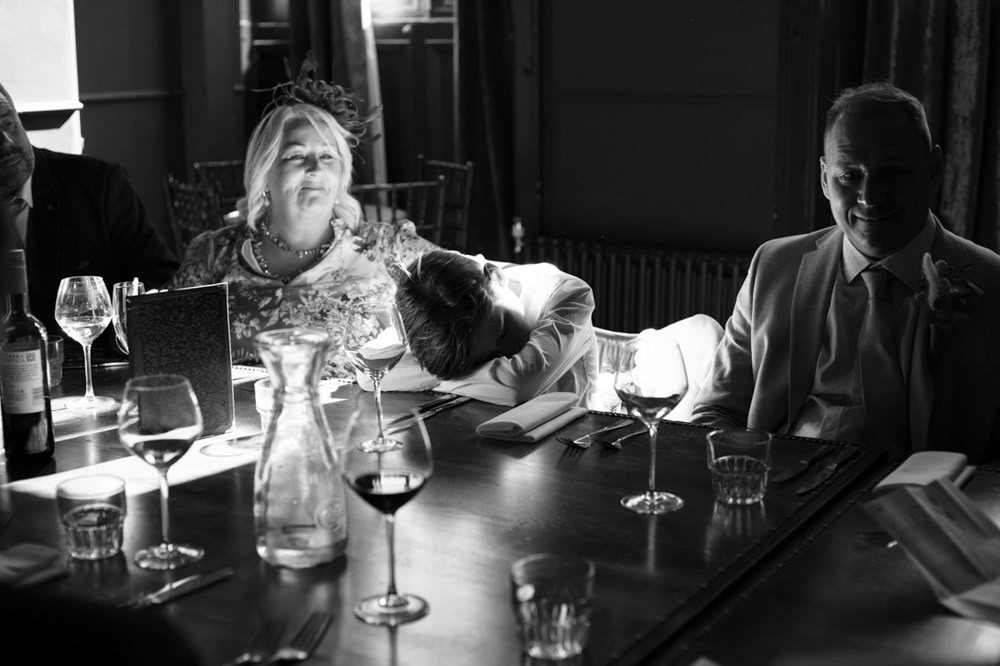 Groom’s son resting his head at the wedding table, tired from the day
