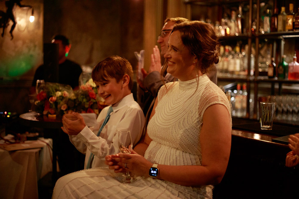 Bride and groom’s son smile and applaud the speech