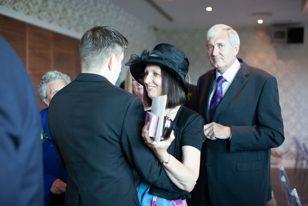 Tim greets his mum warmly, both smiling.