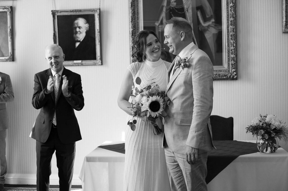 Bride smiling at her groom after the ceremony, surrounded by congratulations