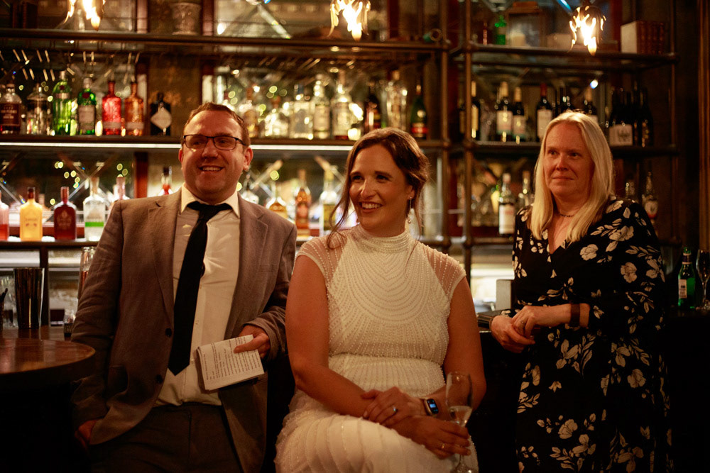 Bride and best man smiling, reacting to groom’s speech