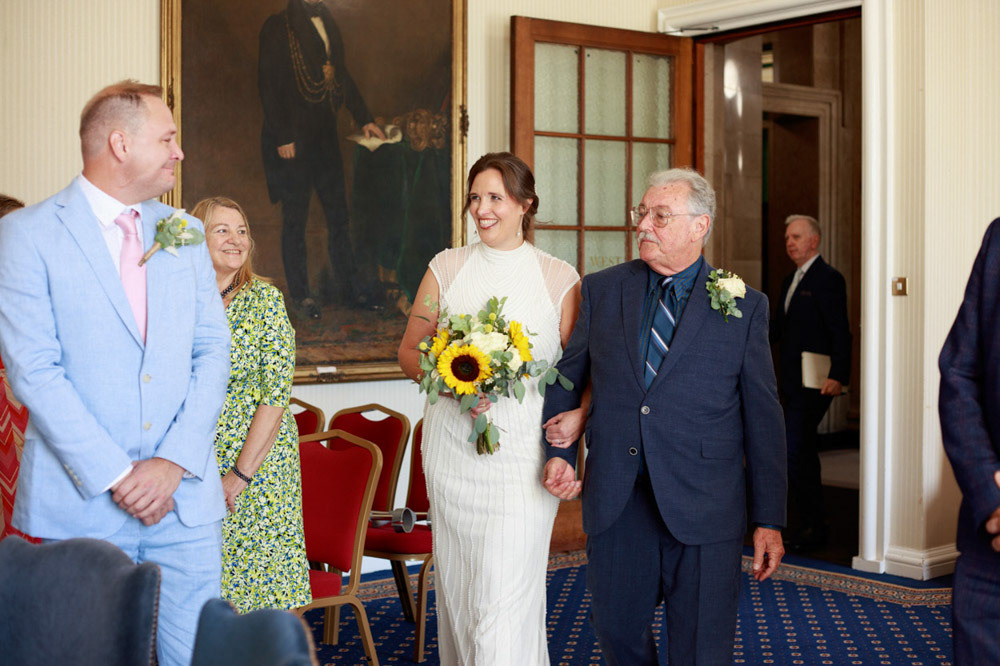 Bride enters Civic Hall with big smiles from both bride and groom