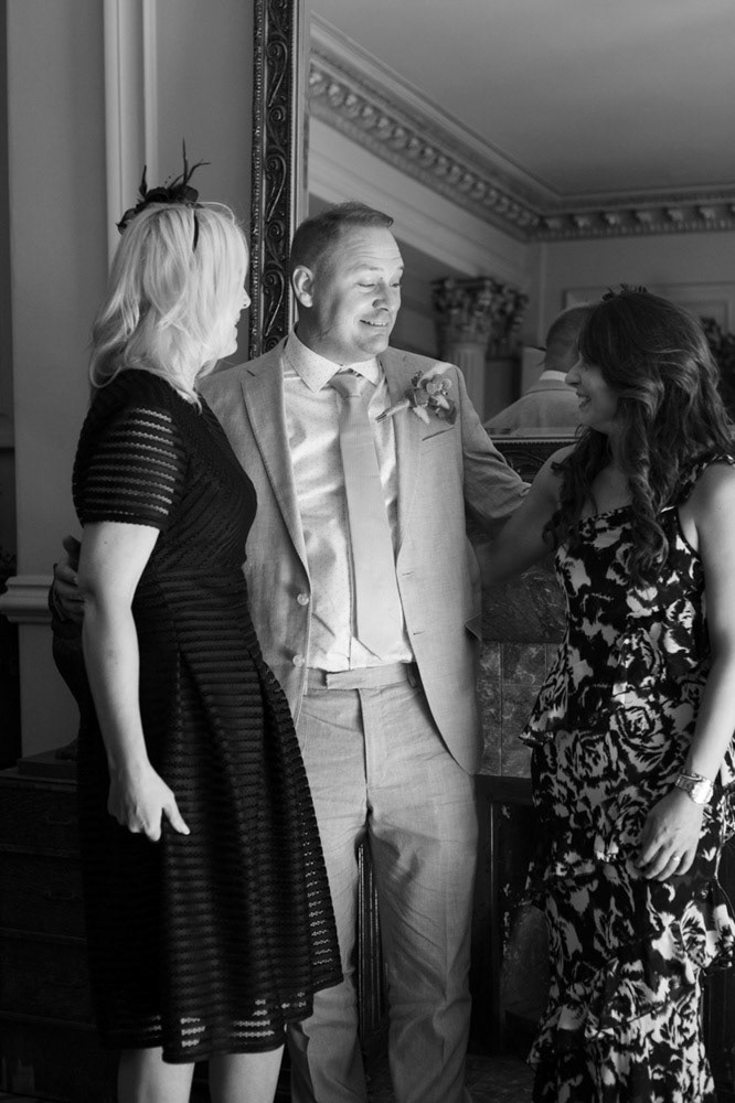 Groom stands for a photo with his two sisters at the Leeds Club