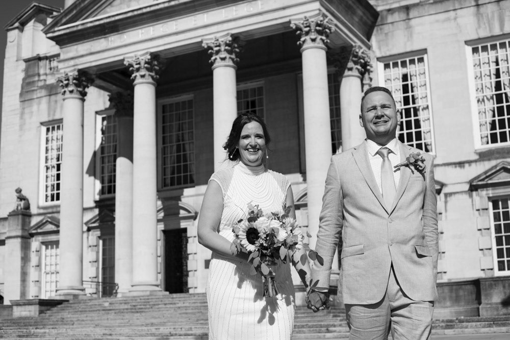 Bride and groom in black and white with Civic Hall columns and smiles