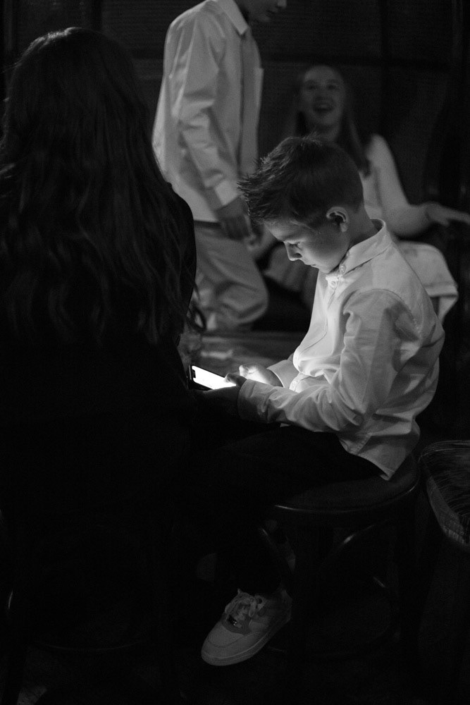 Groom’s son focused on his phone during the reception