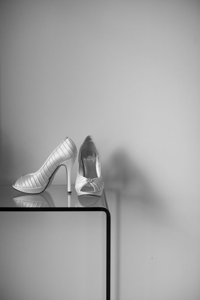Bride’s wedding shoes placed on a glass table, elegant and modern.
