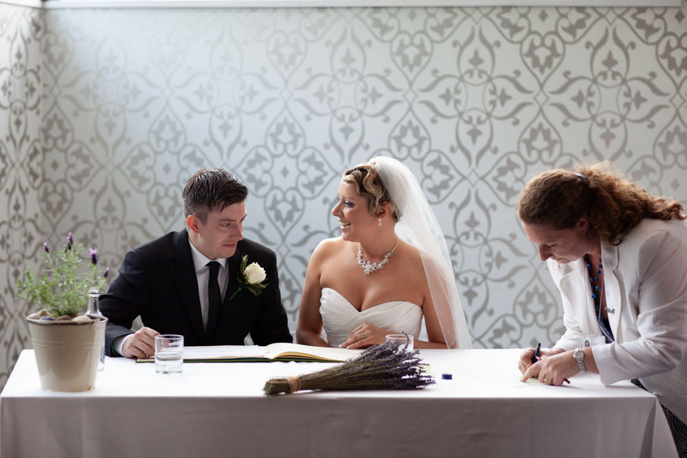Couple share a look as they finish signing the wedding register.