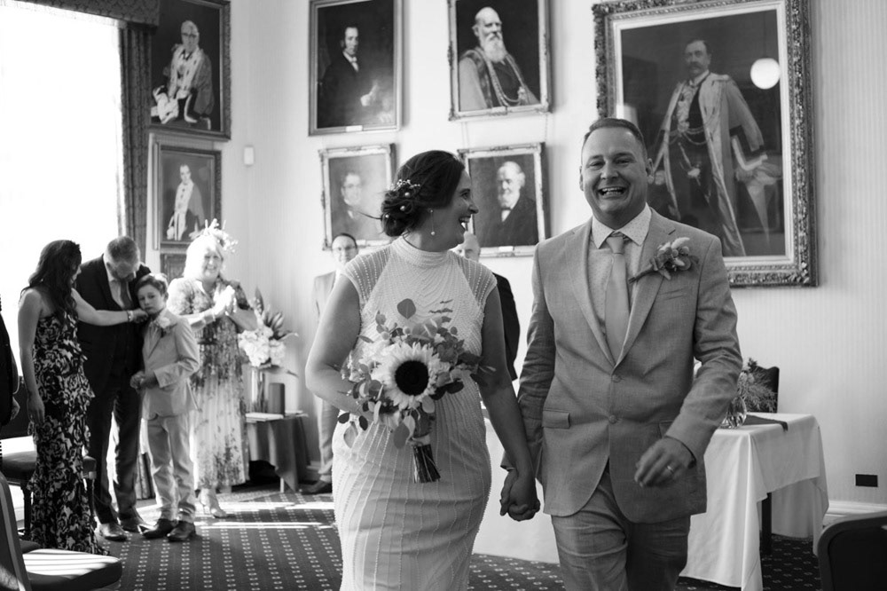 Bride and groom exiting the ceremony room at Leeds Civic Hall, smiling together