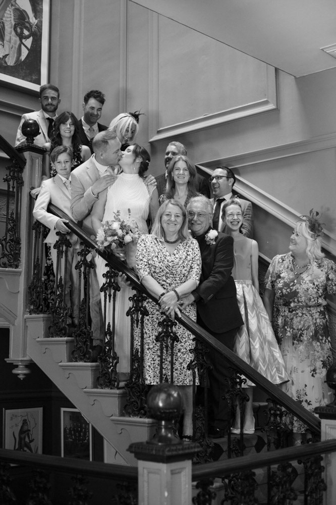 Wedding guests gather for a group photo on the interior stairway