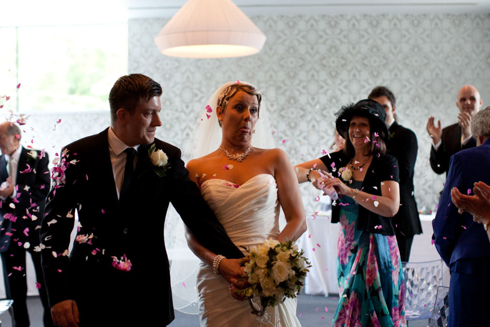 Sam pulls a playful face as she and Tim exit to confetti.