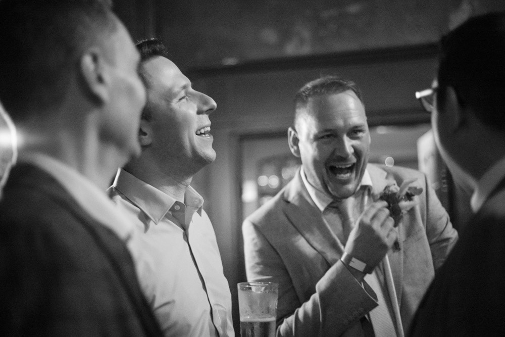 Groom laughing with his friends at the reception