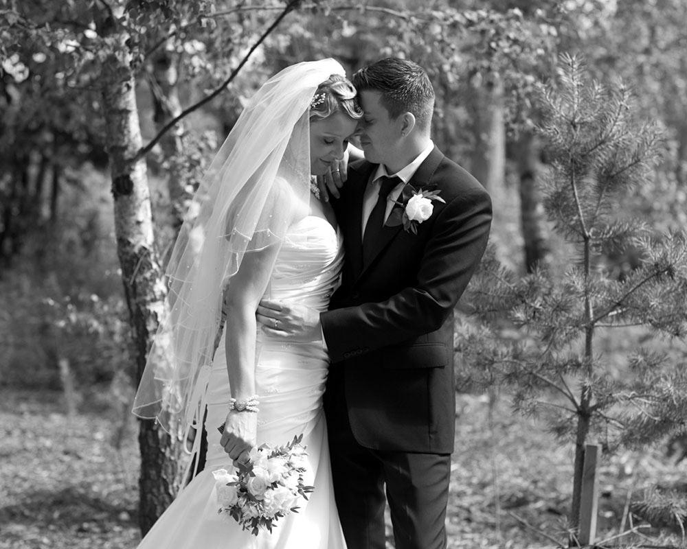 Unposed black and white photo of a couple sharing a quiet moment in woodland near Leeds, Yorkshire