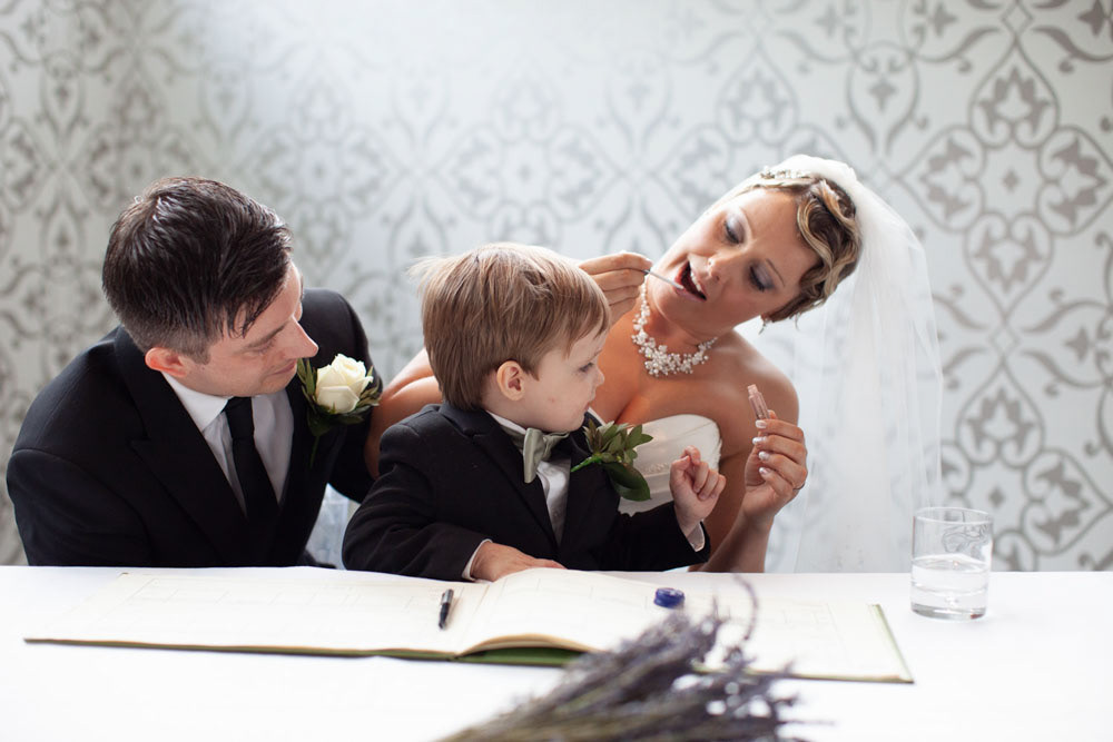 At the register table, Sam applies lip gloss as their son joins them.