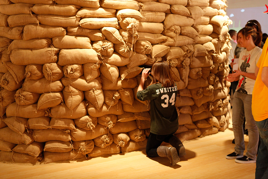 A gallery visitor on opening night using the 'binoculars' to view small sections of the large painting mounted inside of the bunker