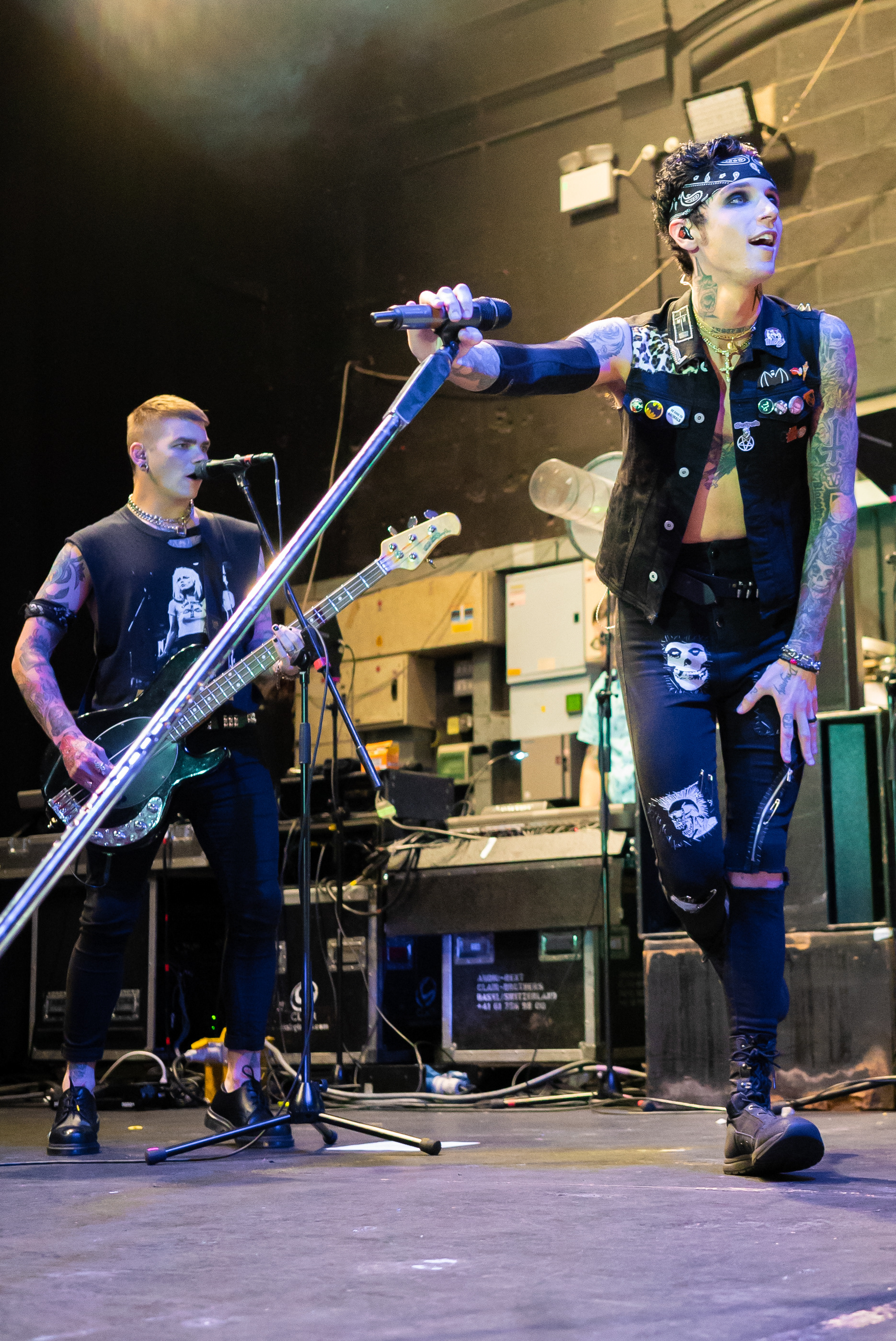 Andy Black leaning over with his microphone stand whilst his guitarist is singing backing vocals behind him