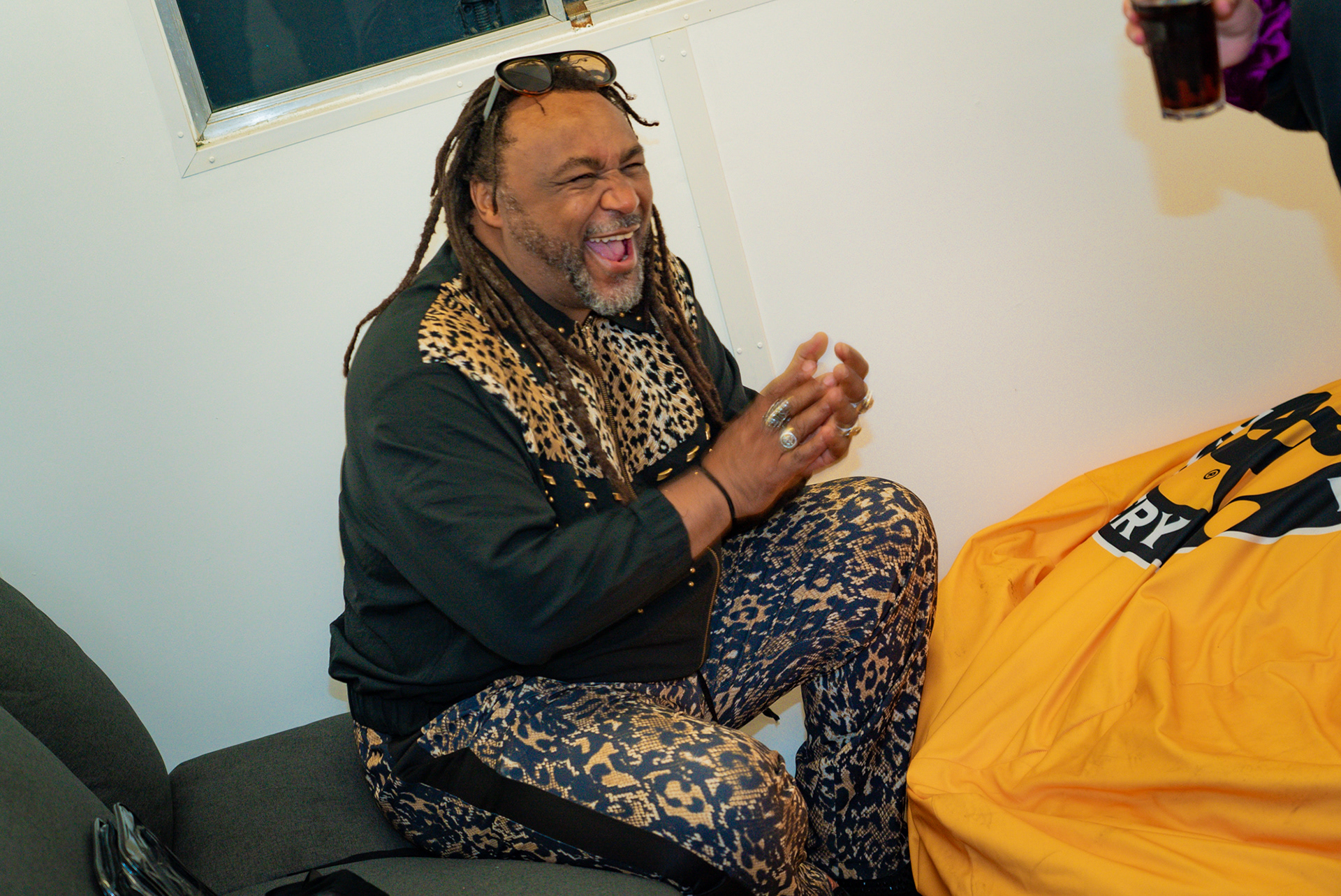 Benji Webbe backstage sitting down laughing.
