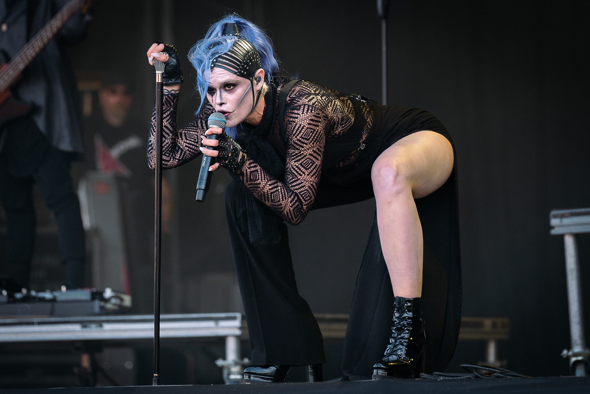 Skynd performing on stage squatting down with a cane.