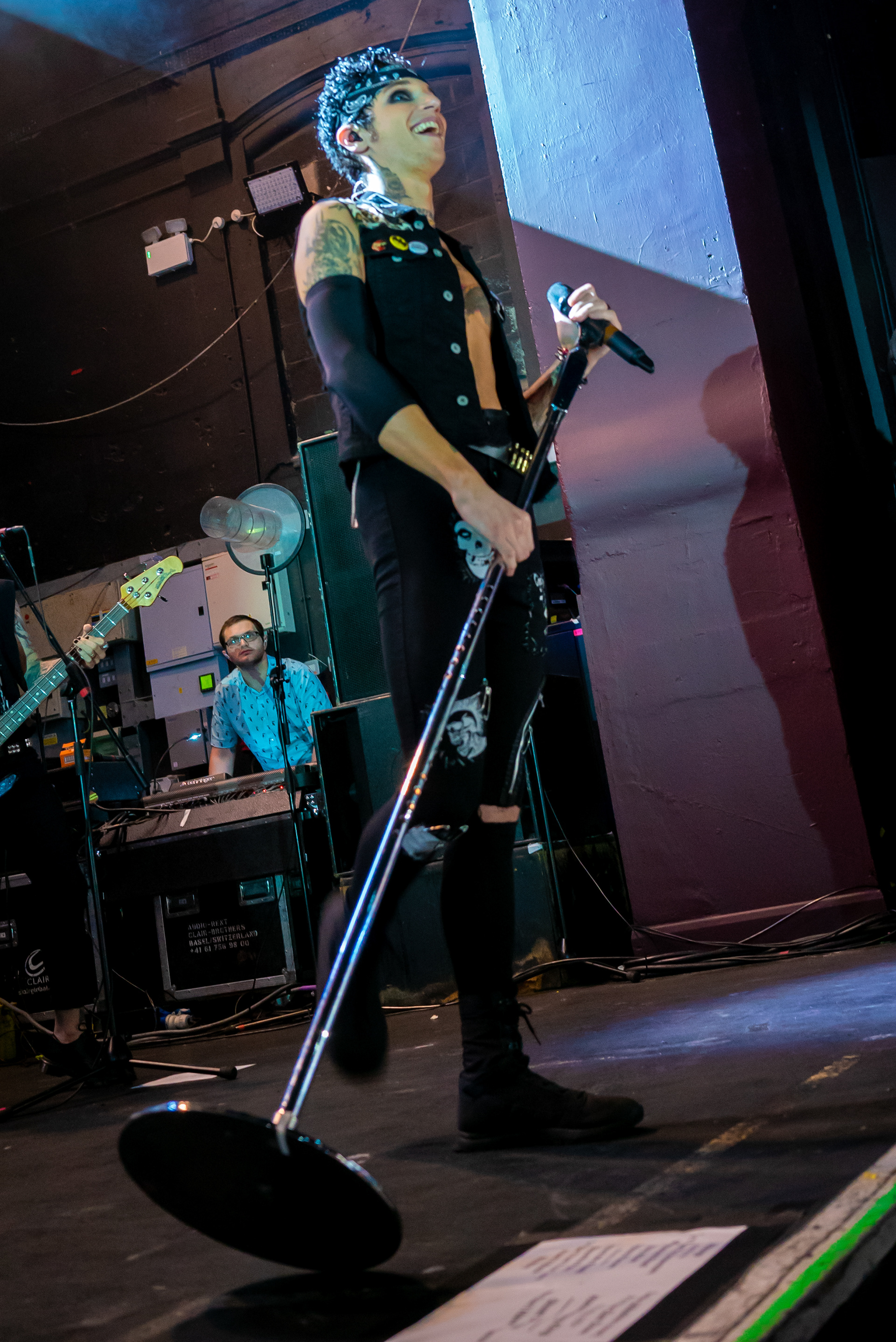Andy Black Holding his microphone stand in front of himself at an angle whilst smiling at the crowd