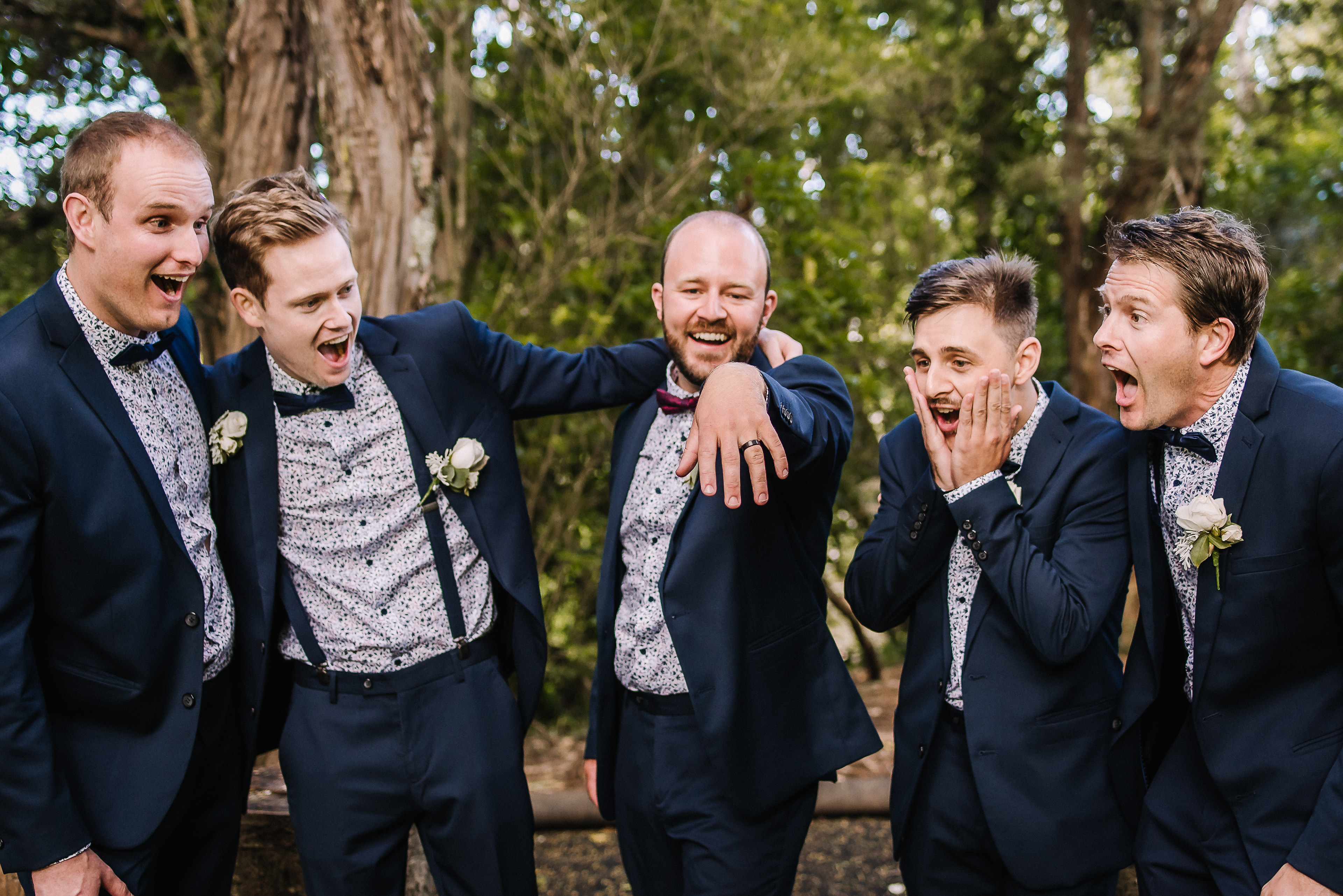 groom shows off his ring to grromsmen