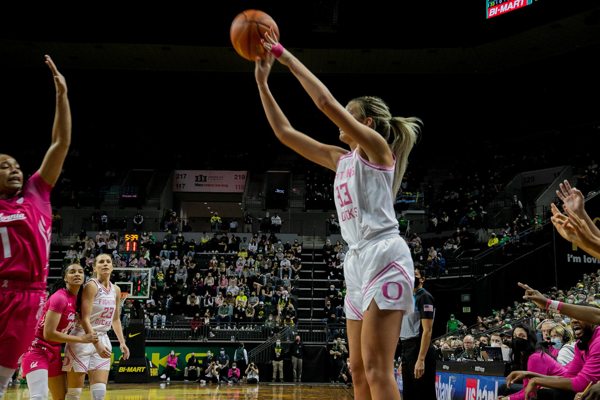 Sydney Parrish shoots a three pointer as her teammates encourage her from the bench with the “three” symbol.