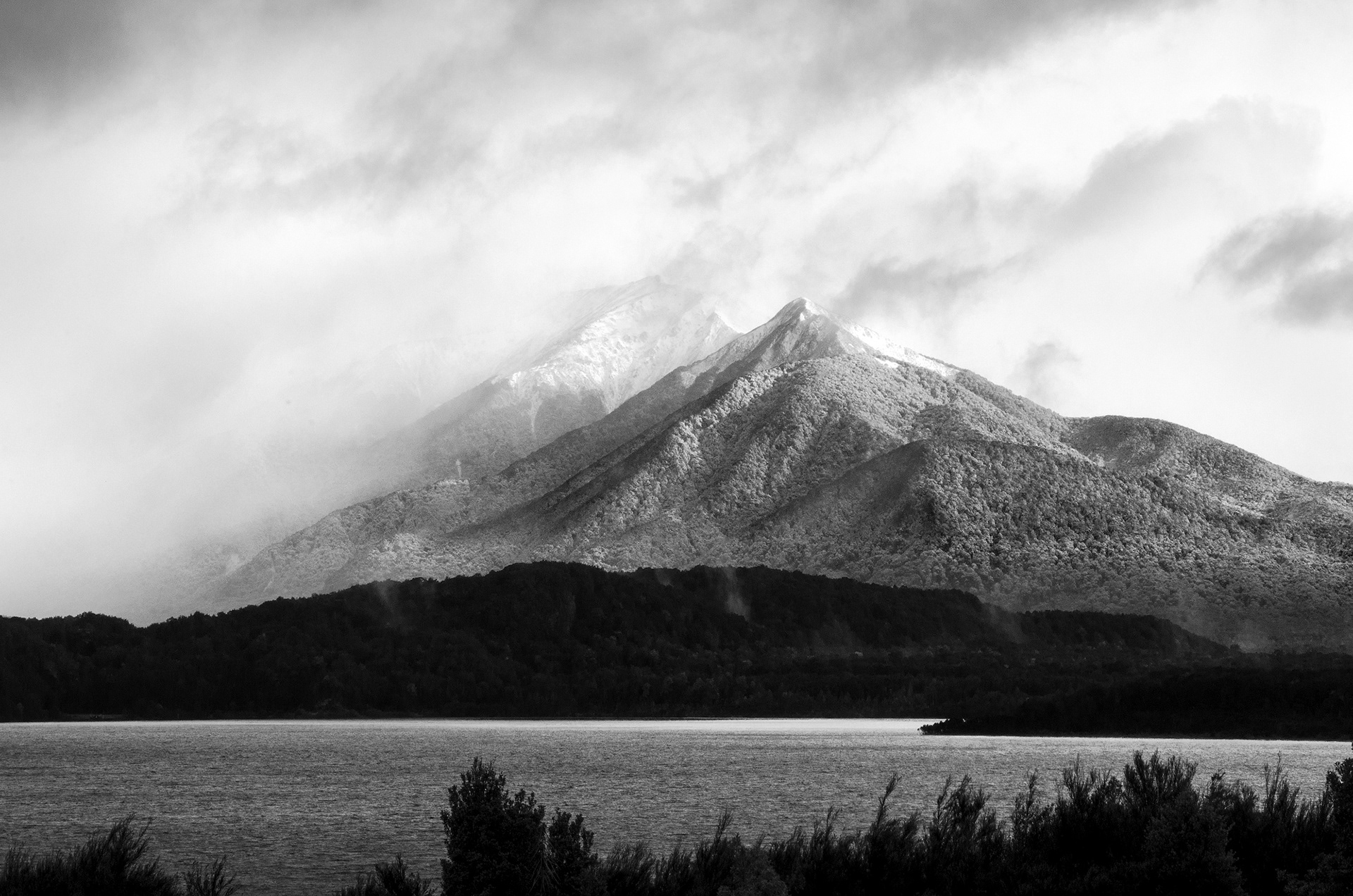 A dusting of snow and low clouds over the Hunter Mountains at Lake Manapouri in New Zealand
