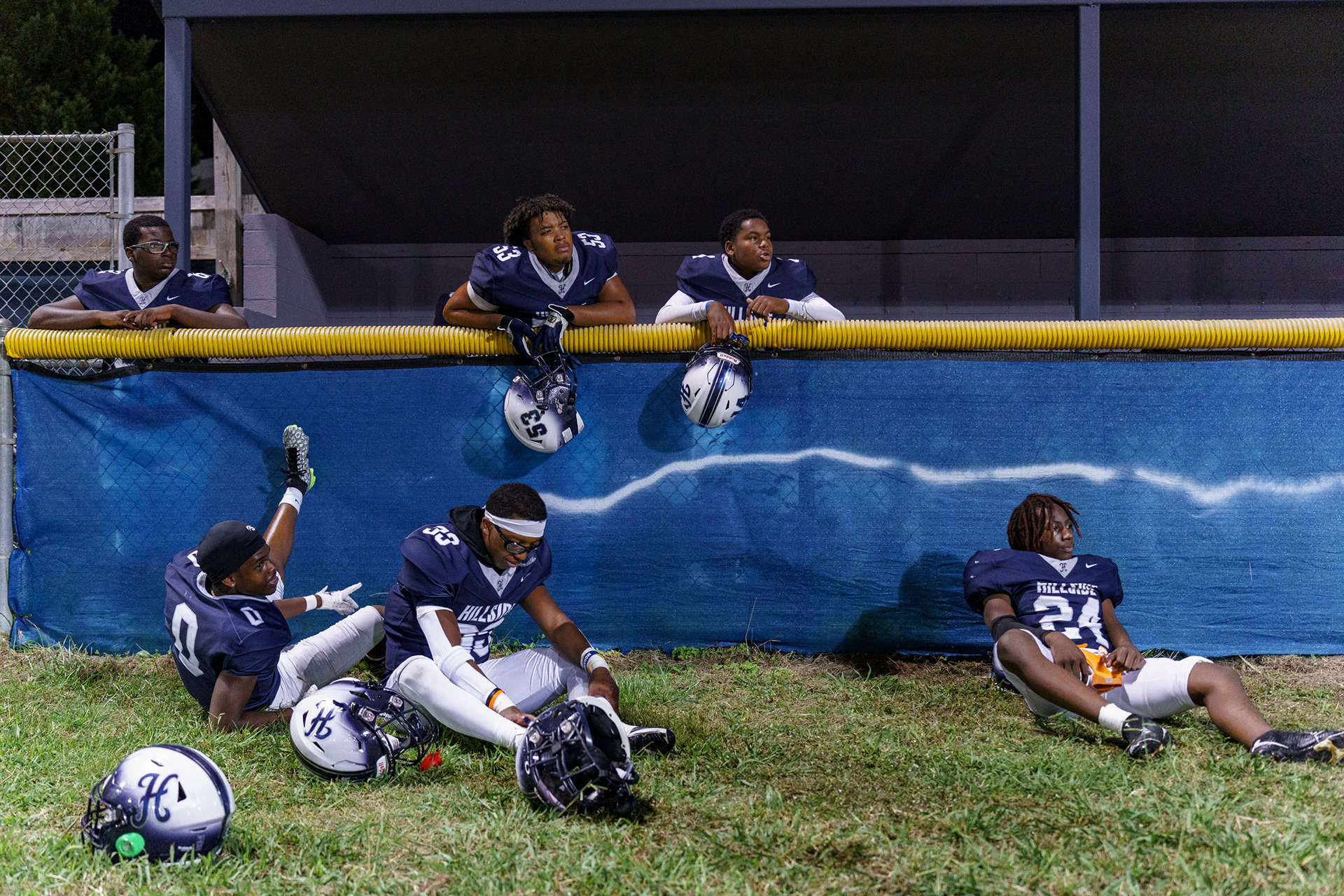Down at halftime, Hillside players rest and recover in the adjacent baseball field while listening to Coach Nowell's game plan.