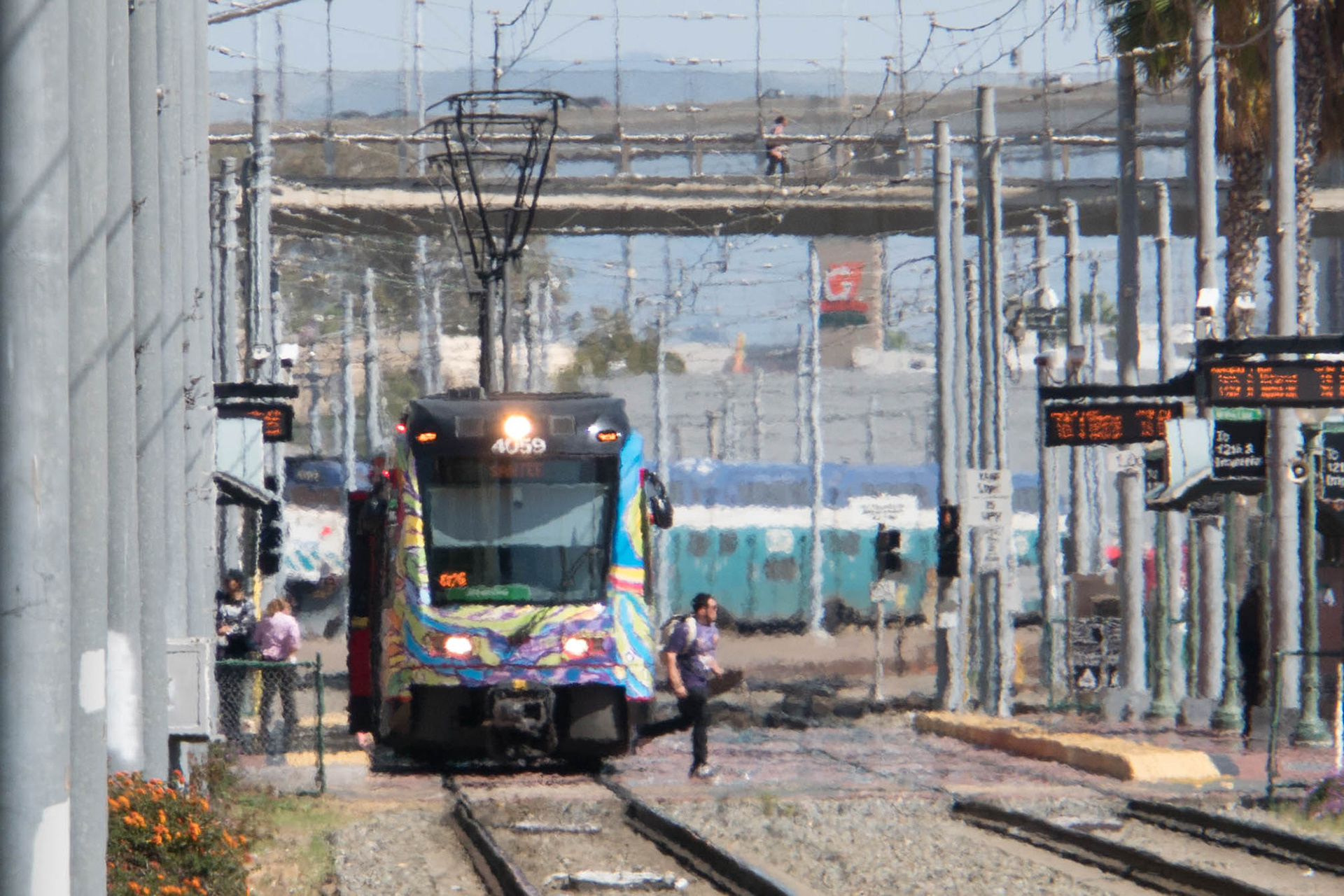 Telephoto shot of a person crossing the railway line in front of a train on a hot day in San Diego
